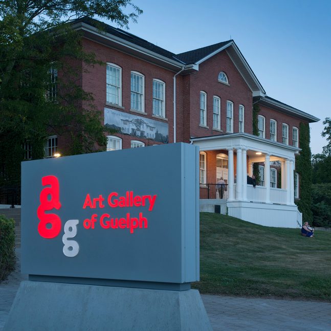 A photograph of the Art Gallery of Guelph building from the outside in front of the building sign.