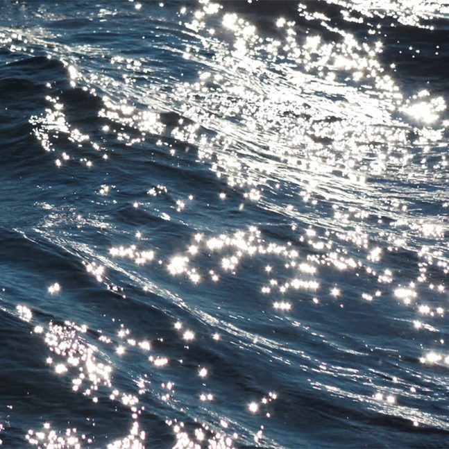 A close-up of sun sparkling on deep blue waves of water