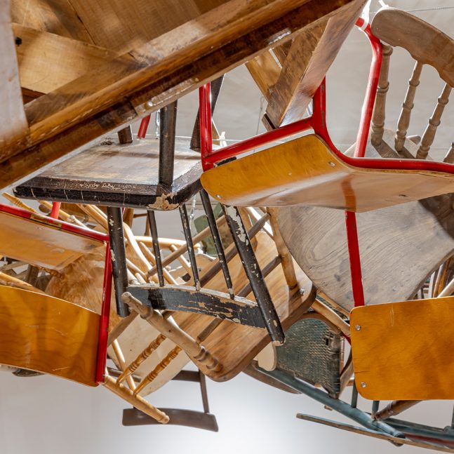 a variety of wooden chair suspended from a white ceiling