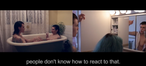 a video still showing a split screen with two people in a bathtub while the other half shows one of the people shaving their upper lip in a mirror. Text below reads "people don't know how to react to that"