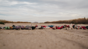 children's toys and clothes arranged in a horizontal line along the ground in the desert