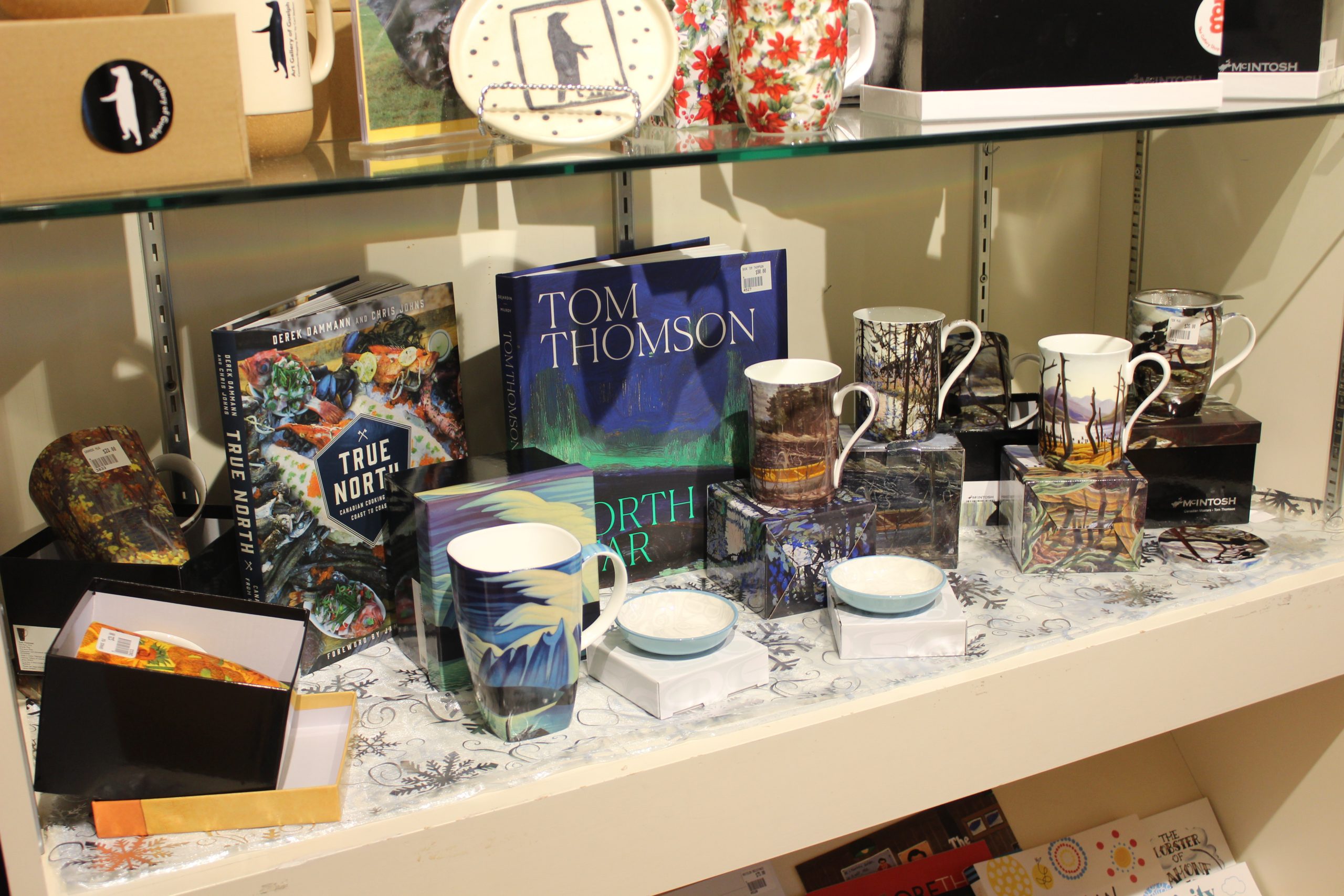 a shelf in a gift shop with mugs, books, and plates