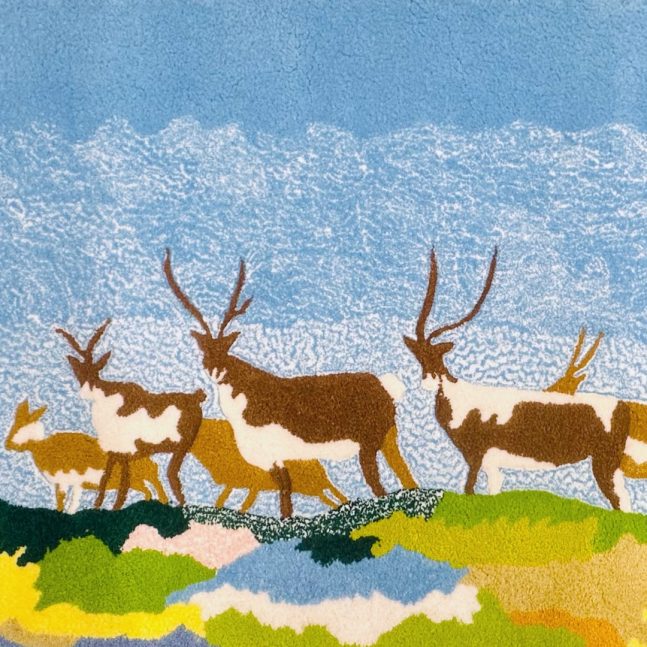 a textile depicting a group of six deer in a multicoloured landscape under a blue and white sky